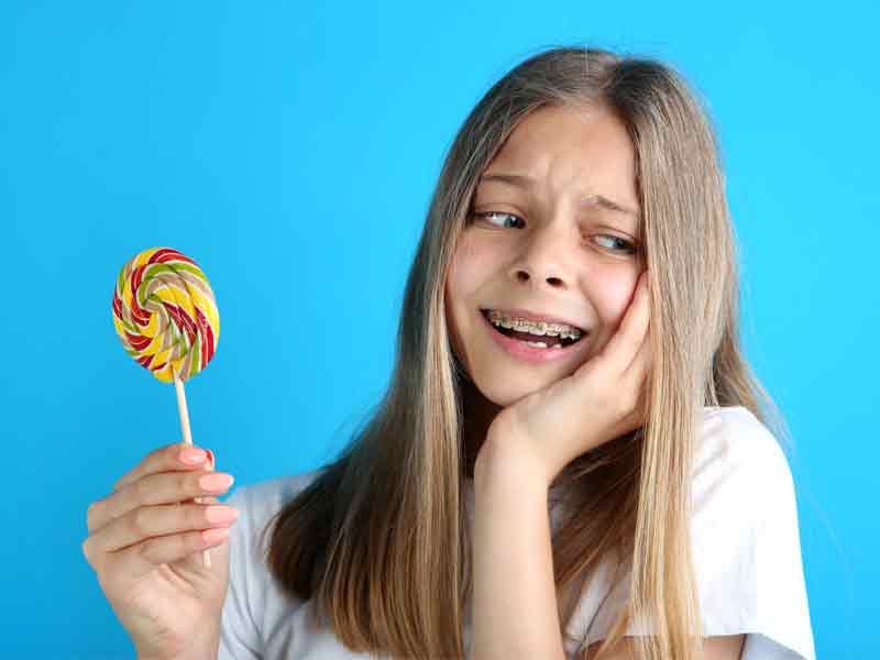 Girl eating hard candy with braces